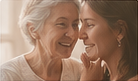 An older woman and a young woman laughing together, foreheads touching.