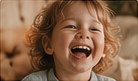 A small child laughing with their eyes shut.